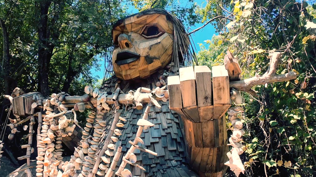 A sculpture of a troll perches in the woods.