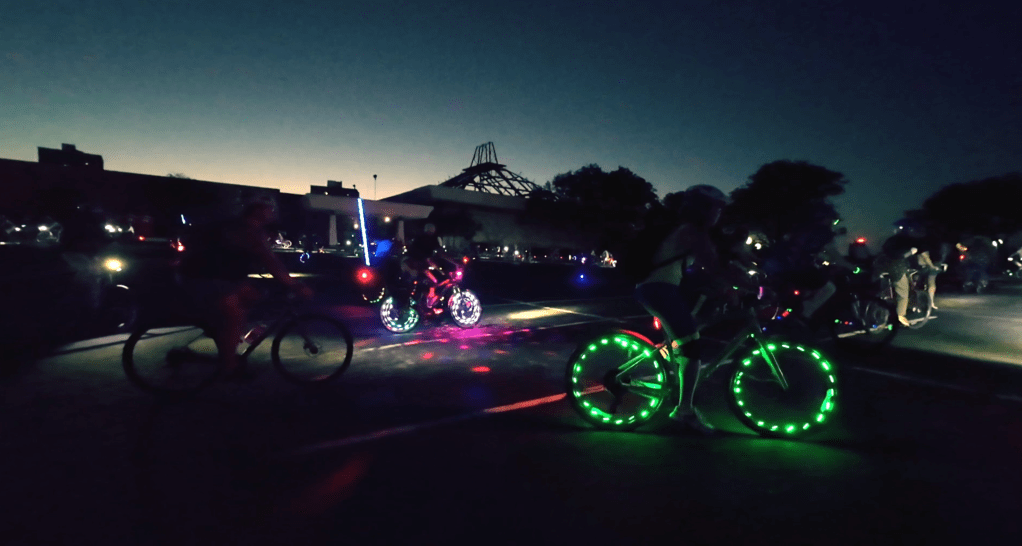Cyclists circle a parking lot at night in Pawtucket, Rhode Island.