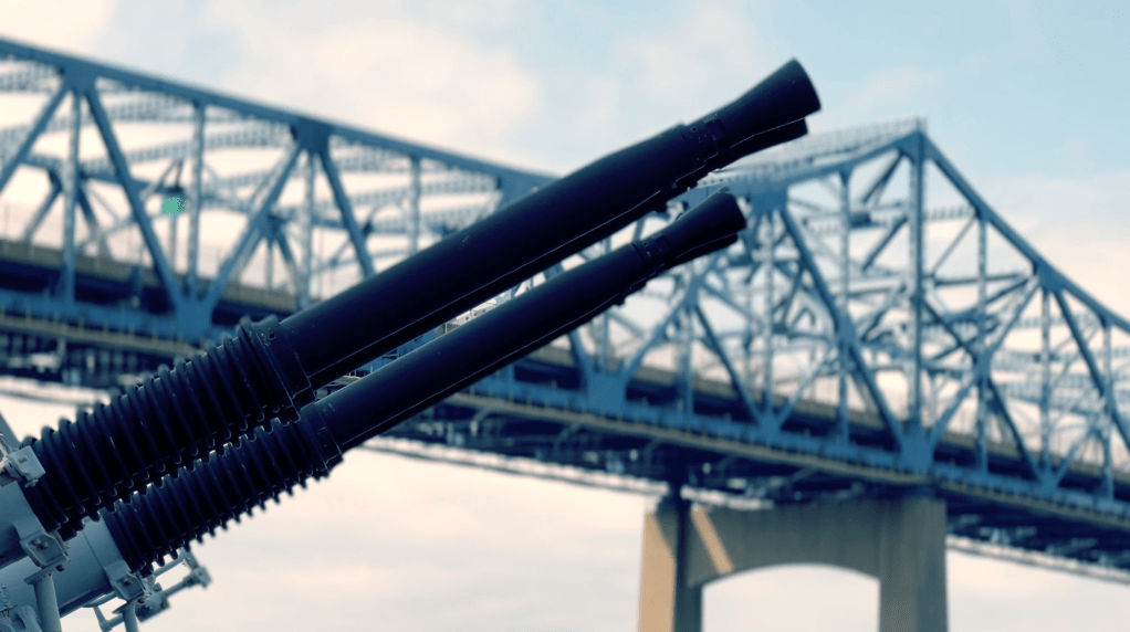 Anti-aircraft guns aim toward the sky in front of a highway bridge in Fall River, Massachusetts.