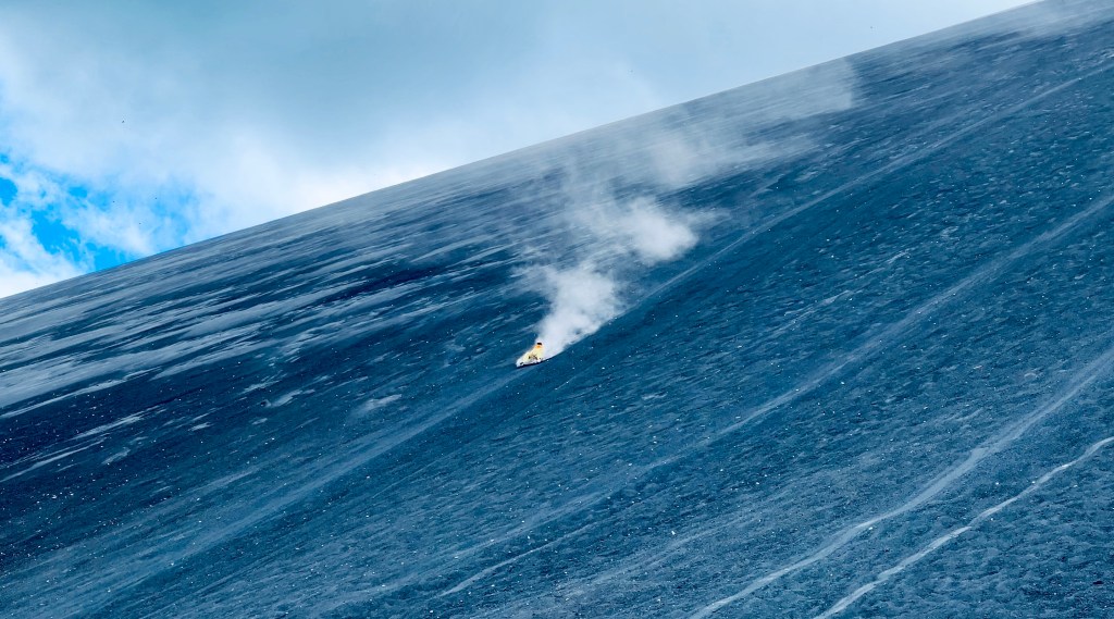 A volcano boarder descends Cerro Negro on a wood plank.